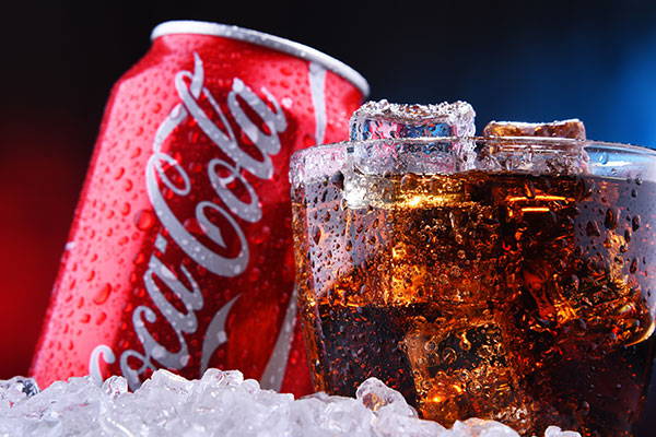 Coca Cola Getränkedose und ein volles Glas cola mit Eiswürfeln