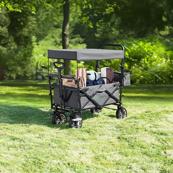 Faltbarer Bollerwagen mit Dach und beladen mit Taschen und Ausrüstung auf einer Wiese