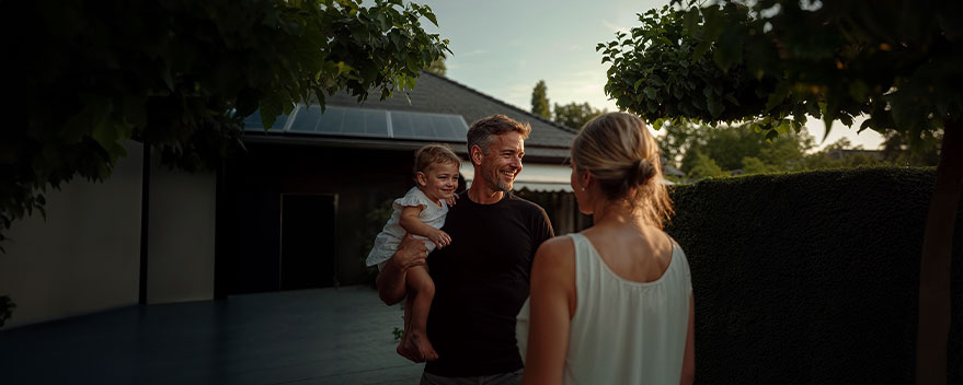 Familie im Garten vor Haus mit Solaranlage auf dem Dach