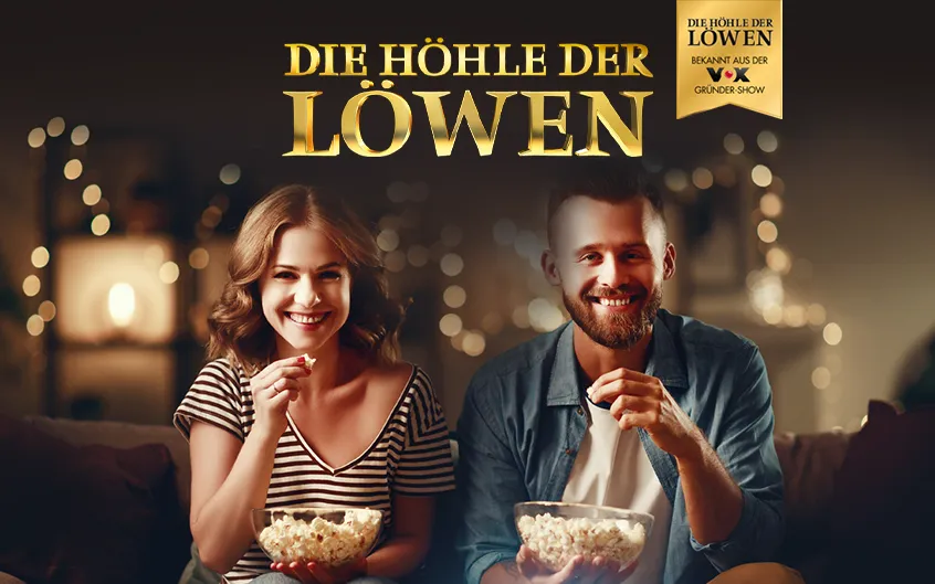 Zwei Personen essen Popcorn und schauen 'Die H&ouml;hle der L&ouml;wen' in einem gem&uuml;tlichen Raum.