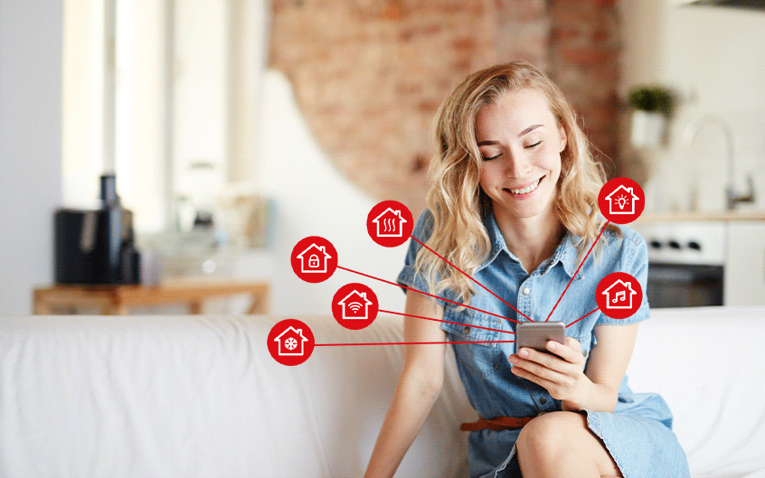 Frau mit Smartphone steuert Smart-Home-Funktionen per App im Wohnzimmer