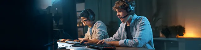 Zwei Gamer mit Headsets spielen am PC in beleuchtetem Gaming-Setup