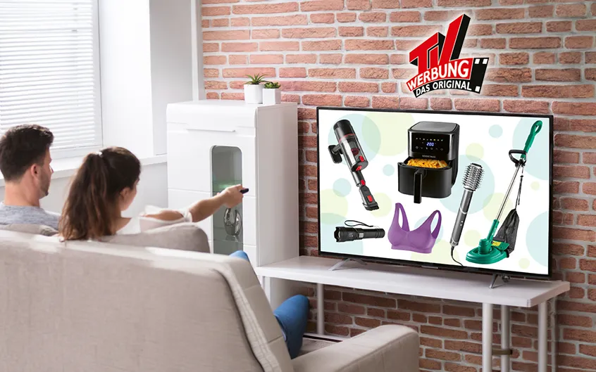 P&auml;rchen sitzt entspannt auf dem Sofa und schaut gemeinsam Fernsehen mit TV Werbung