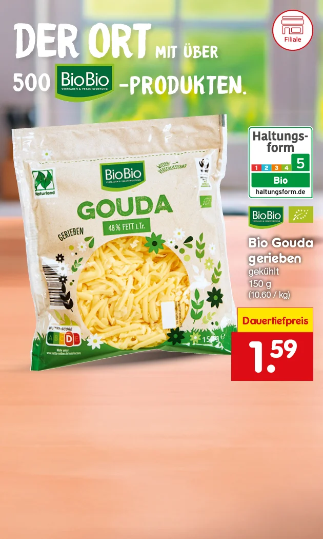 Die Grafik zeigt einen hellen, leicht verschwommenen Hintergrund in Gr&uuml;n- und Naturt&ouml;nen, auf dem eine Packung BioBio Gouda gerieben (150 g) im Vordergrund steht. Oberhalb ist der Schriftzug &bdquo;Der Ort mit &uuml;ber 500 Bio-Produkten&ldquo; abgebildet. Links sieht man die Haltungsform-Kennzeichnung mit Stufe 5 (Bio), rechts den hervorgehobenen Aktionspreis von 1,59 &euro;. Unten befindet sich der Button &bdquo;Hier mehr erfahren&ldquo;.