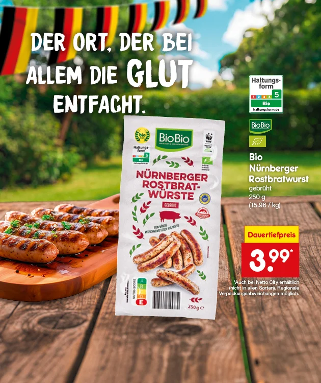 Diese Grafik zeigt auf einem Holztisch gegrillte N&uuml;rnberger Rostbratw&uuml;rste auf einem Holzbrett vor einem unscharfen Hintergrund in Deutschlandfarben, daneben die Verpackung von BioBio Bio N&uuml;rnberger Rostbratwurst, gebr&uuml;ht, mit Bio-Siegeln, Haltungsform f&uuml;nf, WWF-Logo und Nutri-Score; links steht der Slogan &bdquo;Der Ort, der bei allem die Glut entfacht.&ldquo;, rechts der Text &bdquo;Bio N&uuml;rnberger Rostbratwurst, gebr&uuml;ht, zweihundertf&uuml;nfzig Gramm, f&uuml;nfzehn Euro sechsundneunzig pro Kilogramm&ldquo; sowie ein rotes Preisfeld mit &bdquo;Dauertiefpreis drei Euro neunundneunzig&ldquo;, unten links ein Filiale-Symbol und unten ein Button &bdquo;Jetzt Angebote entdecken&ldquo;, der zum Klicken einl&auml;dt.