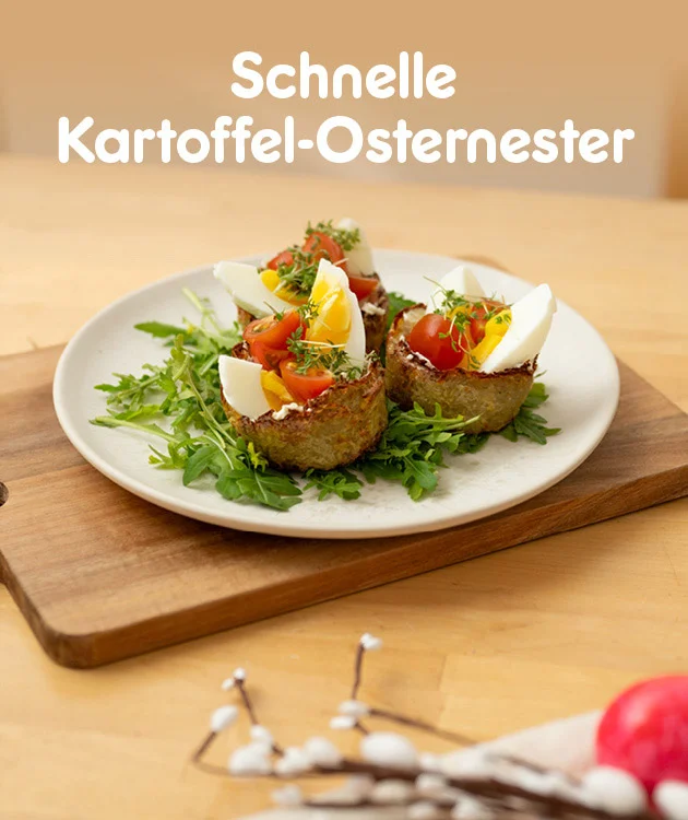 Warmer K&uuml;chenhintergrund mit Holztisch. Links oben steht gro&szlig; &bdquo;Schnelle Kartoffel-Osternester&ldquo;. In der Mitte steht ein wei&szlig;er Teller auf einem Holzbrett mit zwei knusprigen Kartoffel-Nestern, gef&uuml;llt und garniert mit Rucola, halbierten gekochten Eiern, Cherrytomaten und Kr&auml;utern. Unten mittig ein wei&szlig;er Button mit rotem Rand &bdquo;Hier Rezept entdecken&ldquo;, der zum Klicken einl&auml;dt.