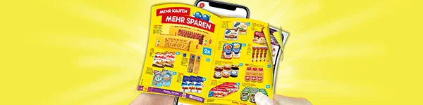 Grafik zeigt eine Hand, die ein ge&ouml;ffnetes Prospekt vor einem Smartphone h&auml;lt. Das Prospekt ist gelb und enth&auml;lt verschiedene Lebensmittelangebote, darunter S&uuml;&szlig;waren, Konserven, Milchprodukte und Wurstwaren. Oben auf dem Prospekt steht in roter Schrift: &bdquo;Mehr kaufen, mehr sparen&ldquo;. Im Hintergrund ist ein gelber Strahlenkranz zu sehen. Unten auf dem Bild befindet sich ein wei&szlig;-roter Button mit der Aufschrift &bdquo;Zum digitalen Wochenprospekt&ldquo;, der zum Klicken einl&auml;dt.