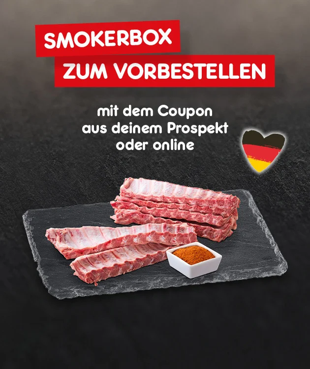Die Grafik zeigt einen dunklen, rauchigen Hintergrund. Oben stehen in zwei roten Balken &bdquo;Smokerbox zum Vorbestellen&ldquo;. Darunter in wei&szlig;er Schrift &bdquo;mit dem Coupon aus deinem Prospekt oder online&ldquo;. Rechts daneben ist ein Herz in Schwarz-Rot-Gold. In der Mitte liegt auf einer dunklen Schieferplatte rohes Fleisch (mehrere Rippenst&uuml;cke) und daneben eine kleine wei&szlig;e Schale mit Gew&uuml;rzmischung. Unten ein wei&szlig;er Button mit roter Umrandung &bdquo;Hier geht&rsquo;s zum Vorbestellen&ldquo;, der zum Klicken einl&auml;dt.