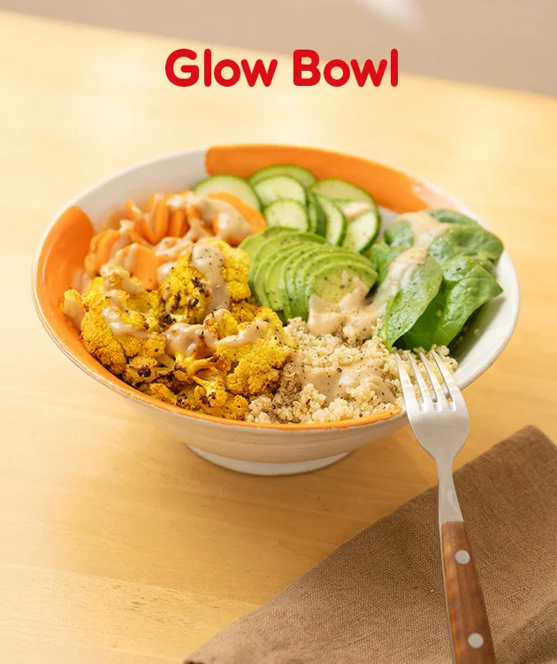 Die Grafik zeigt einen festlich gedeckten Tisch mit einem wei&szlig;en Teller, auf dem ein Baumstriezel steht, der mit zwei Kugeln Eis gef&uuml;llt ist. Links neben dem Teller liegt ein silberner L&ouml;ffel auf einer roten Serviette. Im Hintergrund sind Tannenzweige und warme Lichter zu sehen. Oben steht in gro&szlig;er roter Schrift &bdquo;Easy Baumstriezel&ldquo;. Unten im Bild befindet sich ein wei&szlig;er Button mit rotem Rahmen und der Aufschrift &bdquo;Hier Rezept entdecken&ldquo;, der zum Klicken einl&auml;dt.