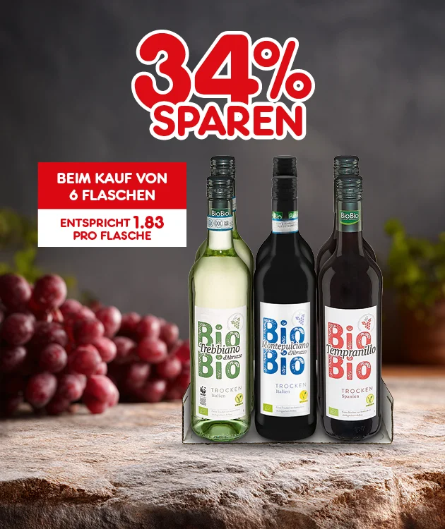 Drei Flaschen Bio-Wein stehen nebeneinander auf einem Holztisch, im Hintergrund liegen rote Weintrauben. Oben steht in gro&szlig;er roter Schrift &bdquo;vierunddrei&szlig;ig Prozent sparen&ldquo;. Links daneben ein rotes Feld mit wei&szlig;er Schrift &bdquo;Beim Kauf von sechs Flaschen, entspricht eins Komma acht drei Euro pro Flasche&ldquo;. Unten befindet sich ein wei&szlig;er Button mit rotem Rand und roter Aufschrift &bdquo;Weitere Sparangebote entdecken&ldquo;, der zum Klicken einl&auml;dt.